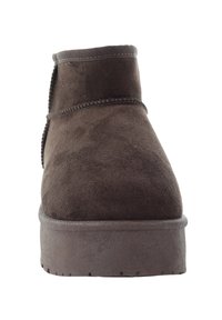 Brązowe zamszowe botki za kostkę z zaokrąglonym noskiem, przeszyciami oraz płaską gumową podeszwą z teksturowanym bieżnikiem zapewniającym przyczepność.