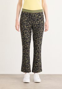 Leopardprint broek in donker groen en zwart met een brede tailleband met groene en zwarte strepen. Het materiaal lijkt zacht en heeft een losse pasvorm.