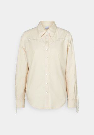 Knappskjorte i lys beige bomull med broderte detaljer og frynser på ermene; har spiss krage og frontknapper.