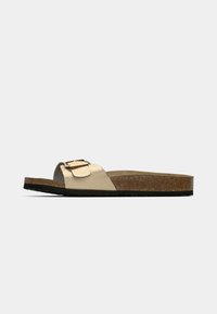 Μονή ταμπά σαγιονάρα με φελλό σόλα και μεγάλο λουράκι με αγκράφα, εμφανίζεται από το πλάι σε απλό λευκό φόντο.