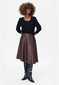 Czarny sweter prążkowany z kwadratowym dekoltem, w połączeniu z brązową skórzaną spódnicą w kształcie litery A i czarnymi za kolano botkami. Elegancki, strukturalny design.