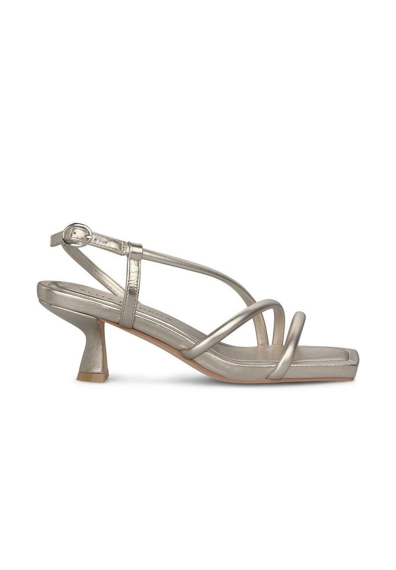 Metallisch zilveren slingback hak met kruislings banden, lage blokhak, vierkante neus, gladde textuur en verstelbare enkelband.