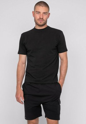 T-shirt noir en coton à manches courtes avec un col rond, associé à un short noir avec des poches à rabat, créant un look monochrome cohérent.