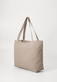 Beige Leinentragetasche mit zwei langen Griffen, rechteckiger Form und weicher Textur, geeignet für den täglichen Gebrauch.