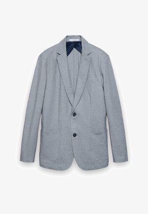 Blazer gris clair avec revers crantés, deux boutons noirs, deux poches plaquées à l'avant, et une doublure intérieure bleu foncé.