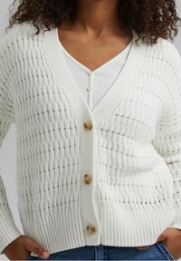 Vit stickad cardigan med ett texturerat mönster, ribbade manschetter och tre stora knappar fram. Lättviktig, öppen design.