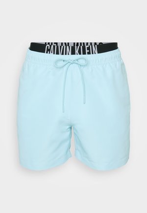 Heledad sinine ujumispüksid, mis on valmistatud siledast kangast. Omavad elastset vöökohta, millel on must-valge "CALVIN KLEIN" logo ja esi nöör.