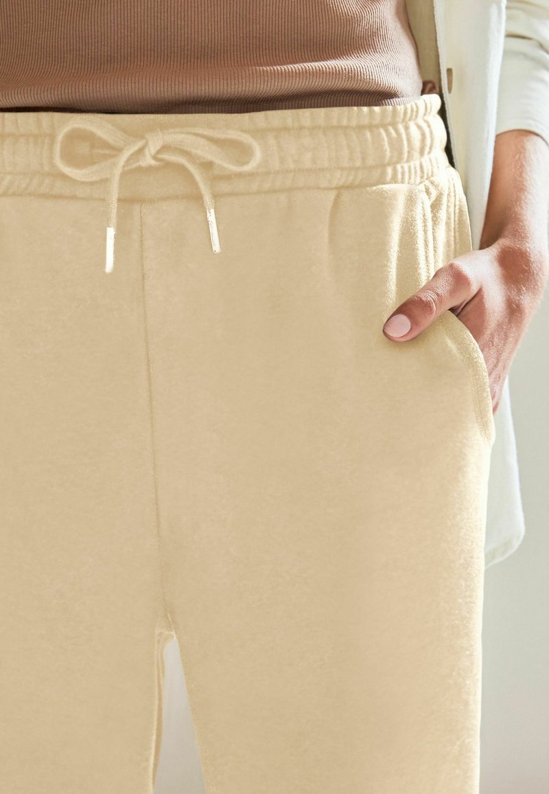 Beige sweatpants med elastisk talje og snoretræk, med sidelommer og en blød tekstur.
