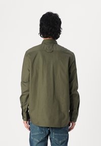 Olijfgroene longsleeve shirt van gladde stof, met een kraag, knoopmanchetten en een rechte zoom met een detail van een middentaille.