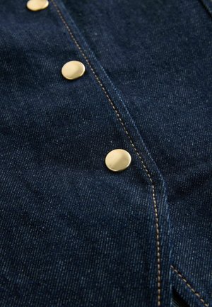 Dark denim fabric featuring a row of round, polished gold buttons, contrasting stitching, and a smooth textured surface.