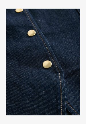 Dark denim fabric featuring a row of round, polished gold buttons, contrasting stitching, and a smooth textured surface.