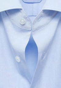 Light blue collared shirt with a button closure, smooth fabric texture, and contrasting stitching on the collar. Buttons are round and clear.