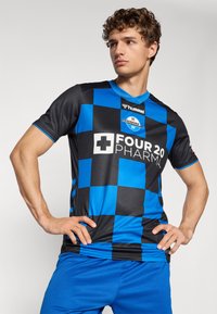 Black and blue checkerboard pattern jersey with a v-neck, featuring a logo on the chest and blue shorts. Smooth, athletic fabric.