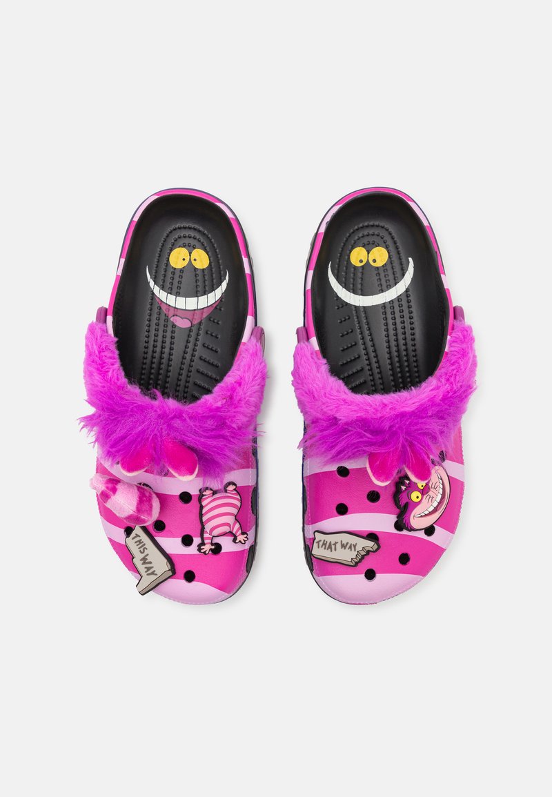 Roze instapklompen met zwarte stippen, fuzzy paarse rand en cartoonfiguren; met gele ogen en glimlachdetails.