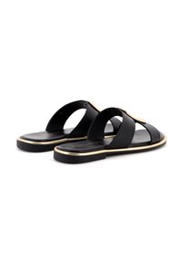 Sandali in pelle nera con due ampie cinghie e un riflesso dorato lungo la suola, dal design flat e aperti sul retro per una facile vestibilità.