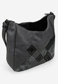 Bolso de hombro de cuero gris oscuro con patchwork negro, tachuelas metálicas, patrones decorativos y una apertura superior con cremallera.