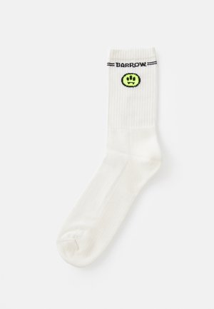Calzino bianco in cotone con texture a costine, che presenta il logo nero "BARROW" e un sorriso verde ricamato sul lato.