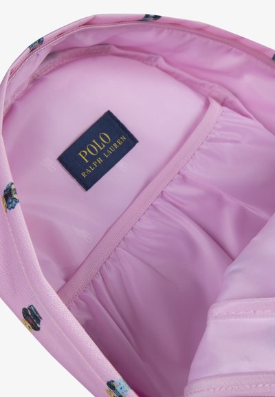 Intérieur rose d'un sac avec une étiquette de marque. La doublure comprend de petits motifs répétés. Texture douce, tissu lisse, bords cousus.