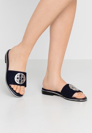 Granatowe zamszowe klapki z zaokrąglonym noskiem, płaską podeszwą i ozdobnym srebrnym elementem na górnym pasku. Gładka faktura i minimalistyczny design.