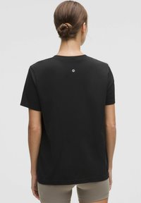 Sort T-shirt med rund hals, korte ærmer og et subtilt logo på ryggen. Fremstillet af blødt, struktureret stof med en afslappet pasform.