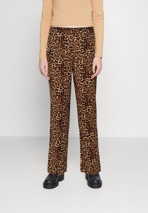 Leopardenmuster, hochgeschnittene Hosen in Braun und Beige, aus strukturiertem Stoff. Gerades Beindesign; kombiniert mit schwarzen Plateauschuhen.