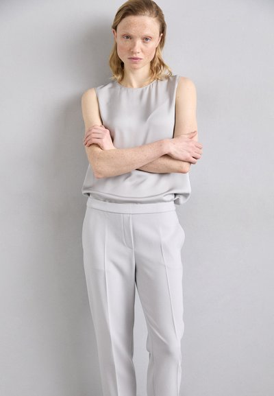 Top senza maniche grigio chiaro abbinato a pantaloni grigi chiari su misura. Tessuto morbido e liscio con una vestibilità rilassata e dettagli di design semplici.
