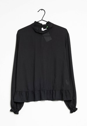 Czarna bluzka z długim rękawem z marszczonym dekoltem, mankietami i dołem, wisząca na czarnym wieszaku na białym tle.