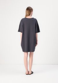Mørkegrå oversized t-skjortekjole med korte ermer, rund halsing og en avslappet passform, som faller over kneet. Glatt stoffstruktur.