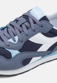 Sneaker con pannelli in rete e sintetici blu navy, accenti bianchi e azzurri, lacci rotondi e suola ammortizzata.