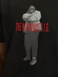Black short-sleeve t-shirt featuring a grey graphic of a figure in a hooded jacket, with red text reading "THE NOTORIOUS B.I.G."