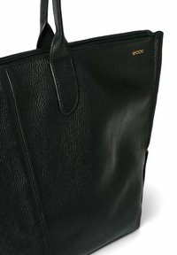 Zwarte leren tote bag met een textuur oppervlak, ritsafsluiting en twee stevige handvatten. Heeft een subtiele gouden logo aan de zijkant.