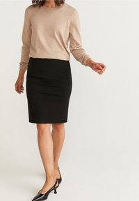 Béžový lehký svetr, černá pouzdrová sukně a černé lodičky na podpatku. Svetr má dlouhé rukávy; sukně je úzká a sahá ke kolenům.