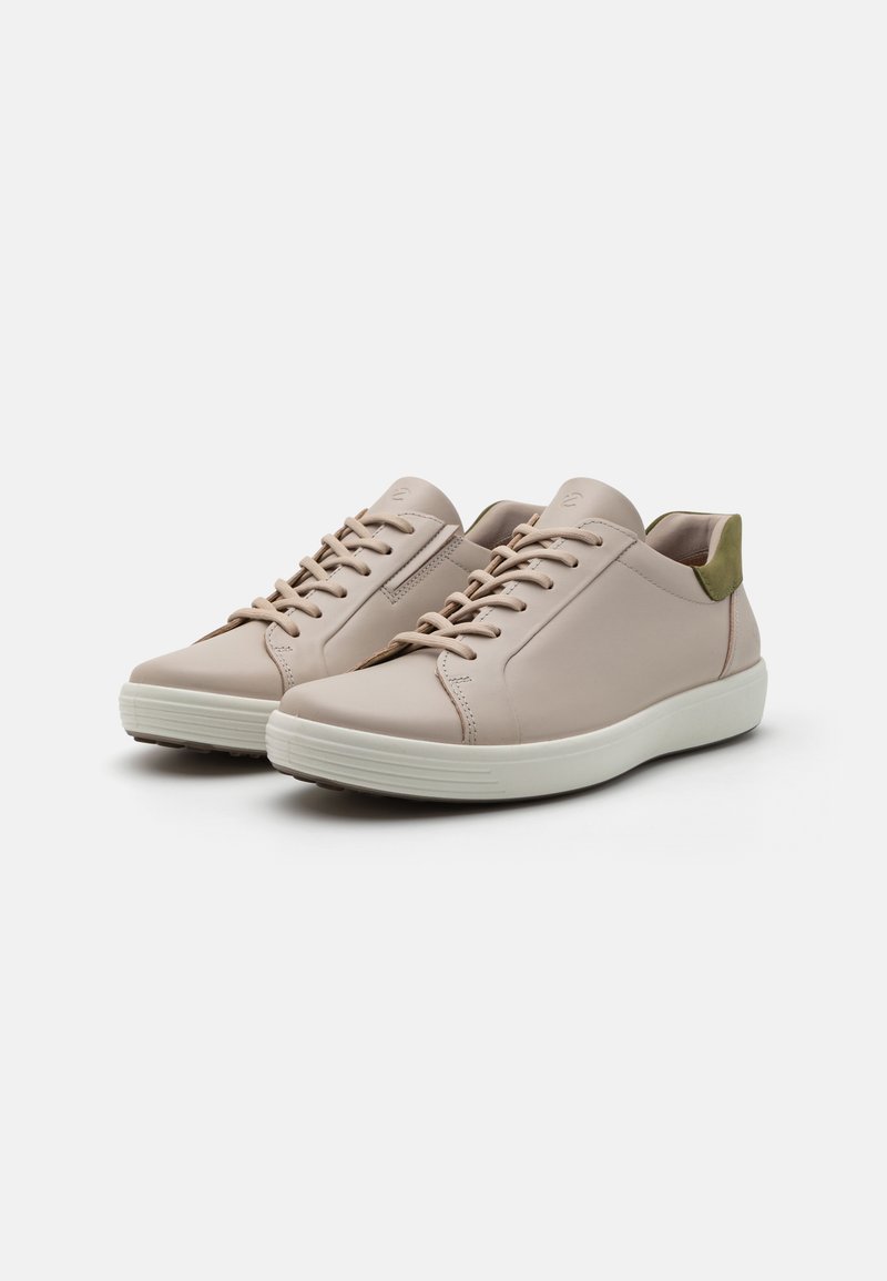 Helle rosa Ledersneaker mit passenden Schnürsenkeln, einem grünen Akzent an der Ferse und einer weißen Gummisohle. Glatte Textur, minimalistisches Design.