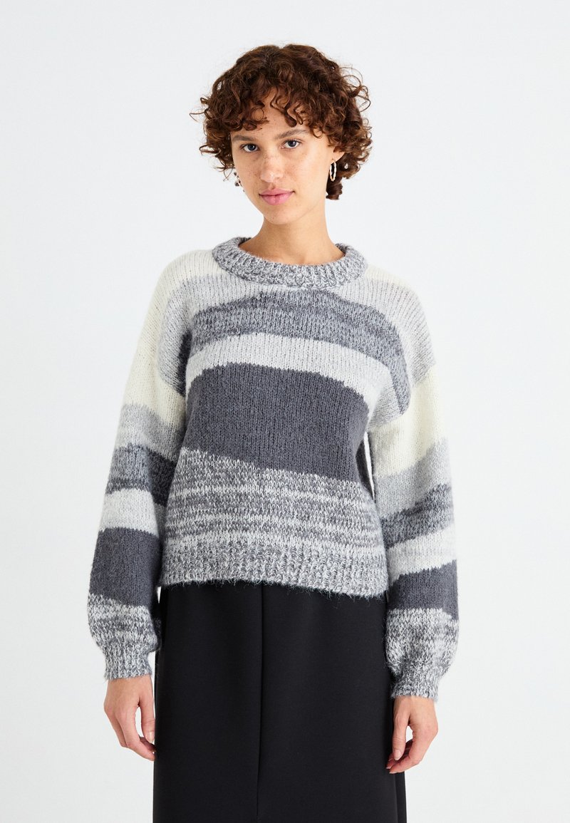 Maglione a righe grigie e bianche in maglia con scollo rotondo, maniche lunghe, motivo testurizzato e orlo corto. Tessuto morbido e peloso.