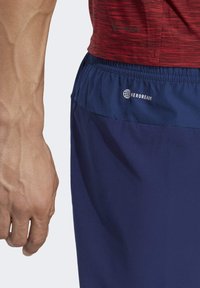 Heren sportshorts in marineblauw met een gestructureerde tailleband, voorzien van het "AEROREADY" logo. De stof lijkt lichtgewicht en ademend te zijn.