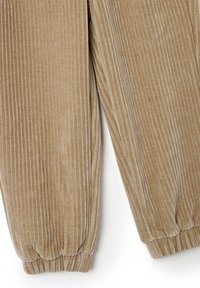 Corduroy broek in een lichtbruine kleur, met verticale ribbelstructuur, elastische cuffs en een zachte, textuurachtige oppervlakte.