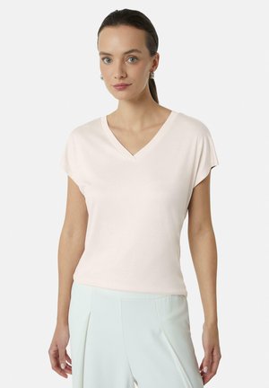Jasnoróżowy t-shirt z dekoltem w serek i krótkimi, podwiniętymi rękawami, wykonany z miękkiego materiału. Noszony z jasnymi spodniami, prezentującymi prosty design.