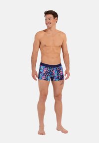Men's swim shorts in a multicolor geometric pattern, featuring a dark blue waistband, made from lightweight, stretchy material.