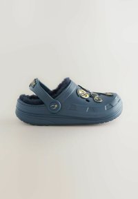 Blauwe klomp met een pluche voering en decoratieve gouden en zwarte bedels bovenop, met een achterkantstrap en ventilatiegaten.