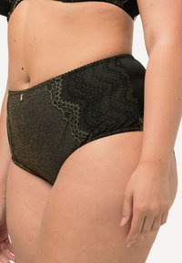Zwarte hooggeplatformde onderbroek met glanzende textuur, kantdetails en golvende randen; voorzien van een klein accent in goudkleurig metaal.