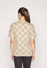 Beige kortermet T-skjorte med teksturert, lappet design som har abstrakte hvite mønstre. Korte ermer, rund hals og en avslappet passform.