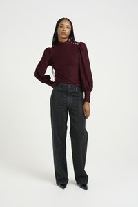 Bordeaux langermet topp med pufferte skuldre og dekorative knapper. Svarte vidde jeans med en teksturert, glitrende finish. Svarte spisse sko.
