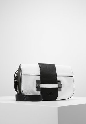 Hvid læder crossbody taske med bred sort rem, sort spænde foran og justerbar sort skulderrem placeret på hvid overflade.