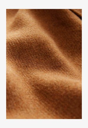 Brun uldstof med en blød, struktureret overflade, der viser bølger og folder, hvilket fremhæver dens varme og tykkelse.