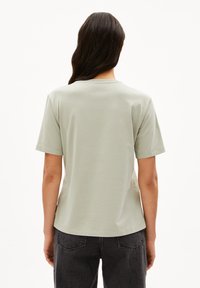 Hellgrünes Baumwoll-T-Shirt mit kurzen Ärmeln, einem Rundhalsausschnitt und einem leicht abgerundeten Saum. Weicher Stoff, minimalistisches Design, keine sichtbaren Logos.