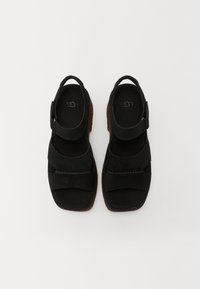 Crne suede sandale s širokim trakama, podesivim kavljem za gležanj, teksturiranim prednjim pojasom, ugodno podstavljenim ulošcima i gumiranim potplatima.