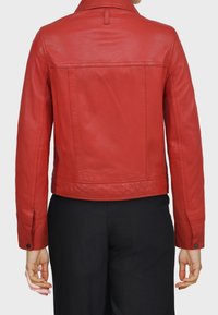 Červená kožená bunda s přiléhavým designem, dlouhými rukávy a hladkou texturou. Obsahuje límec a detaily na zadním švu.