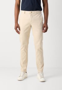 Beige slim-fit broeken van katoen, met een knoopsluiting, voorkwijlen en een gladde textuur. In combinatie met witte sneakers.