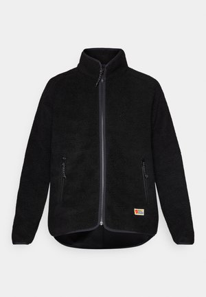 Black fleece jacket with a full zipper, two side pockets, high collar, and a small logo on the lower left side. Soft texture, regular fit.