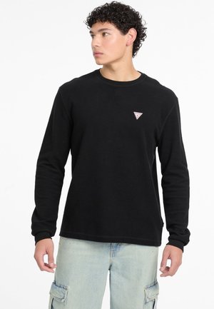 Sort langærmet t-shirt med rund hals, der har et lille trekantet logo på brystet og ribbede manchetter. Blød tekstur og afslappet pasform.